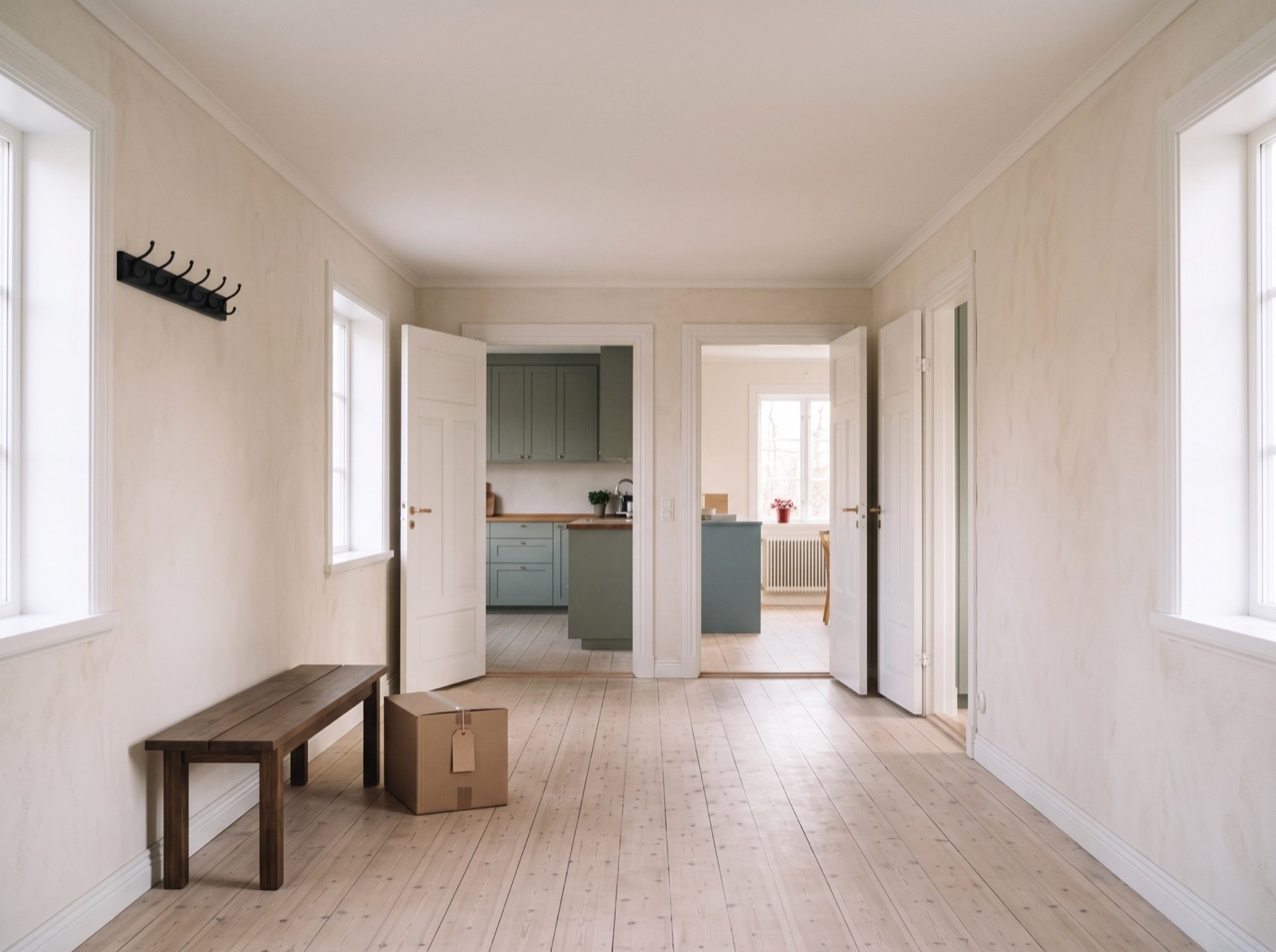 A pale Swedish hallway with a wooden bench, a folded wool blanket, a red mug and labelled moving boxes